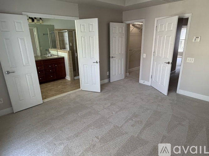 A room with carpeted floor and four doors.