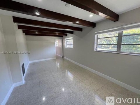 A spacious room with a large window and a tiled floor.