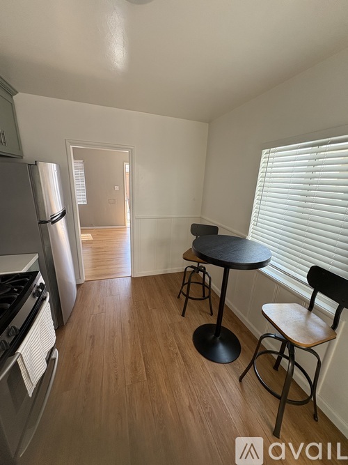 A kitchen with a refrigerator, stove, and a dining table with two chairs.