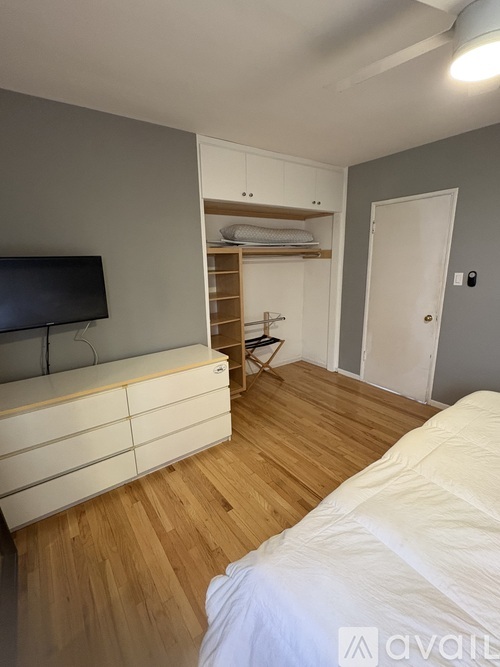 A bedroom with a bed, a TV, and a cabinet with shelves.
