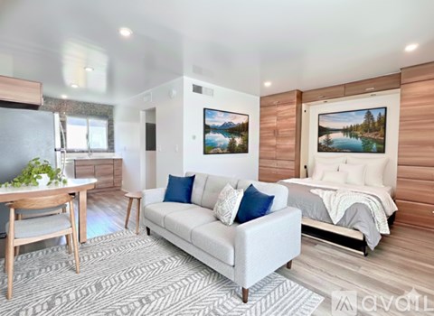 A modern bedroom with a large bed, a couch, and a dining table.