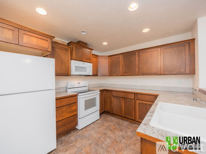 A kitchen with brown cabinets and white appliances.