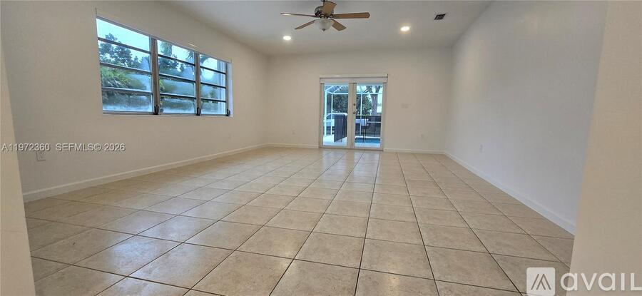 A spacious room with tiled flooring and a ceiling fan.