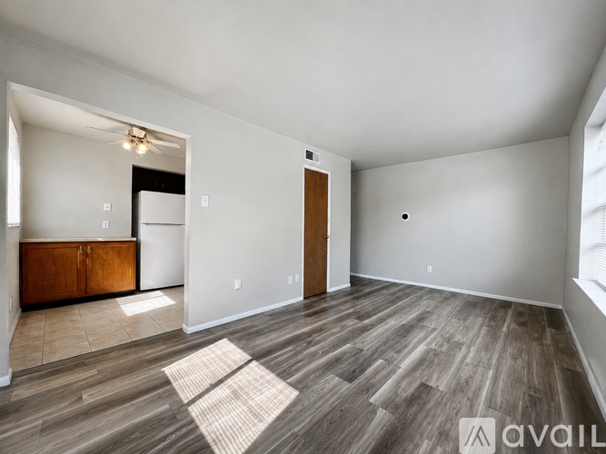 A spacious room with wood flooring and a large window.