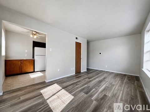 A spacious room with wood flooring and a large window.