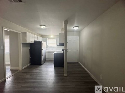 A kitchen area with a black refrigerator and a black trash bin.