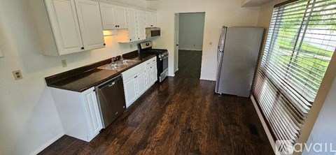 A kitchen with white cabinets and a black counter top.