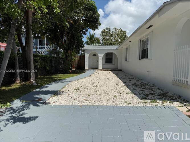 A white building with a gravel driveway in front.