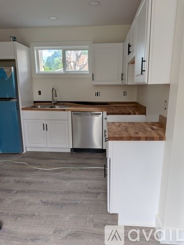 A kitchen with white cabinets and a blue fridge.