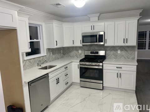 A kitchen with white cabinets and a marble countertop.