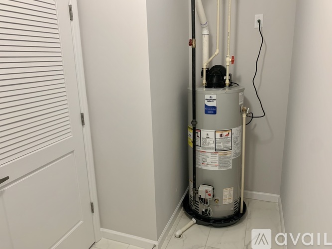 A water heater in a room with white walls and a door with blinds.