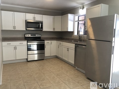 A kitchen with white cabinets and a stainless steel refrigerator.