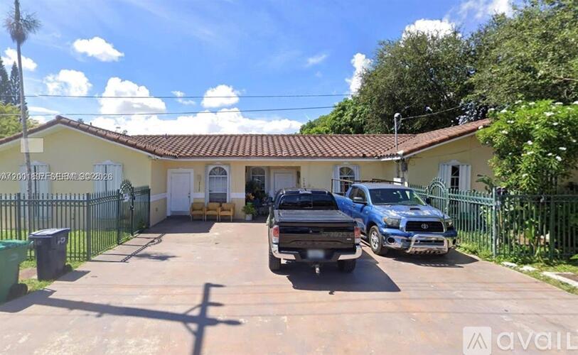 A yellow house with a blue truck parked in front.