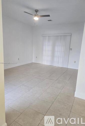 A room with a ceiling fan and a window with blinds.