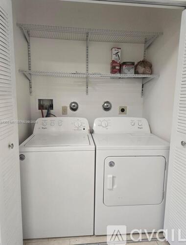 A small laundry room with two washing machines and a shelf above them.