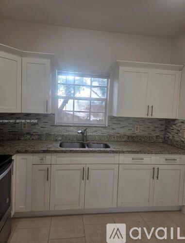 A kitchen with white cabinets and a granite countertop.