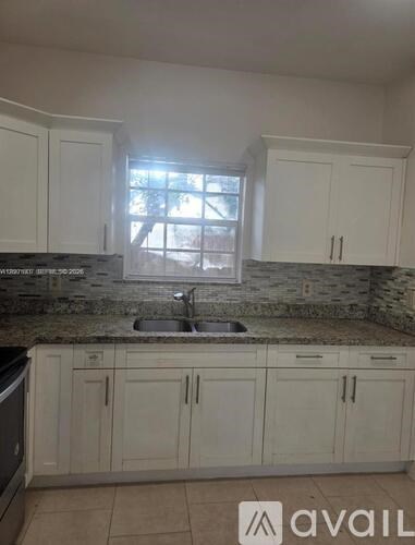 A kitchen with white cabinets and a granite countertop.