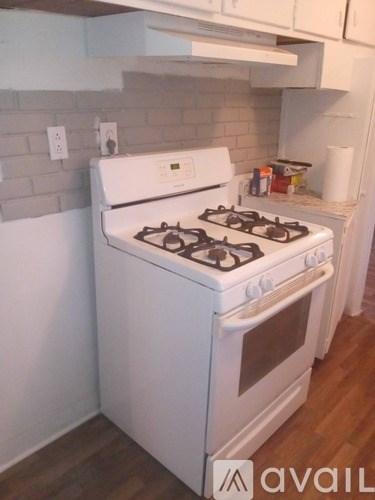 A white gas stove in a kitchen with wooden floors and white cabinets.
