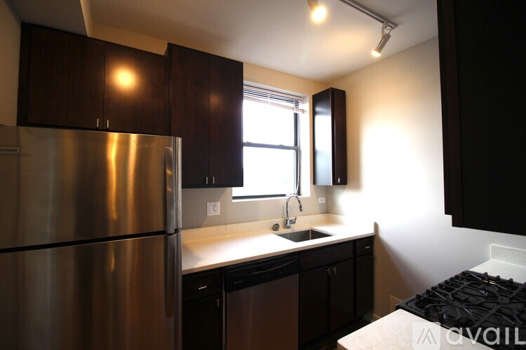 A kitchen with a stainless steel refrigerator and black cabinets.