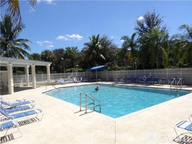 A pool surrounded by chairs and trees.