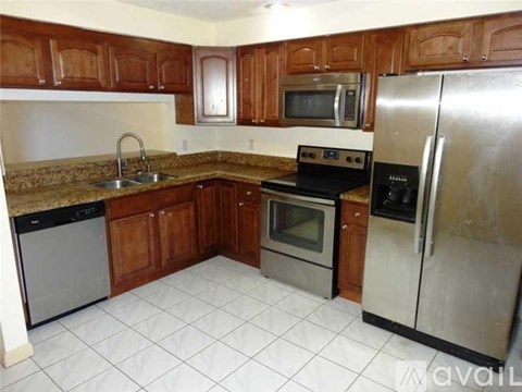A kitchen with brown cabinets and a white refrigerator.