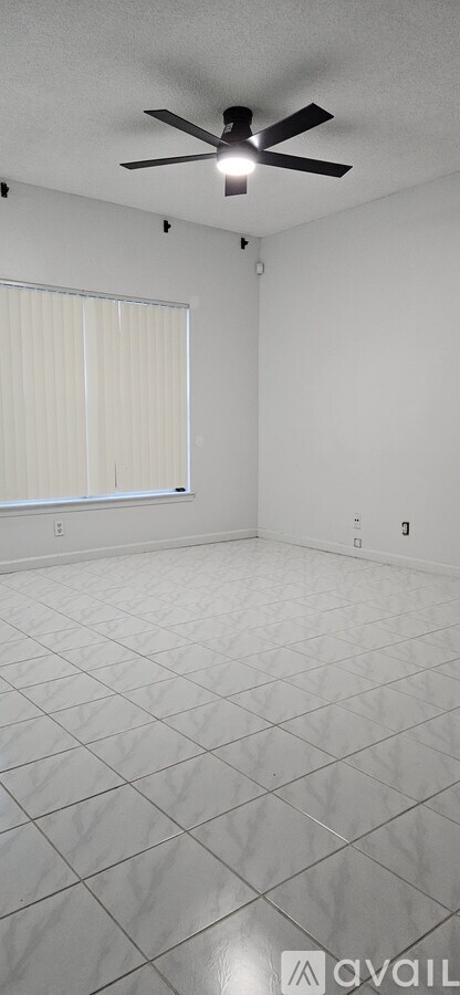 A room with a ceiling fan and a window with blinds.