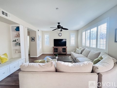 A living room with a white couch and a ceiling fan.