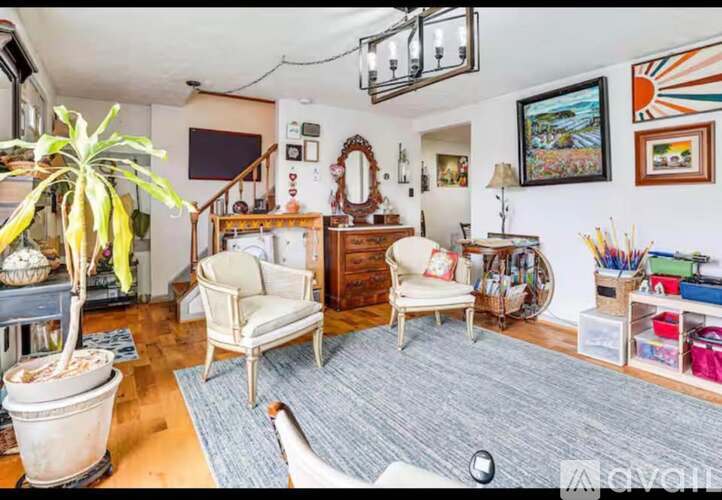 A living room with a couch, chair, and potted plant.