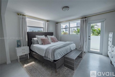 A bedroom with a large bed and a window with curtains.