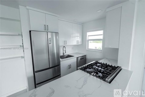 A modern kitchen with a stainless steel refrigerator and a marble countertop.