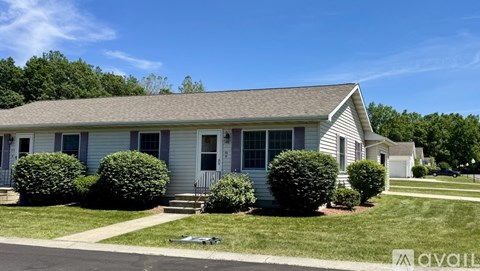 A house with a lawn and bushes in front.