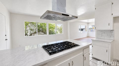 A modern kitchen with a stove top and white cabinets.