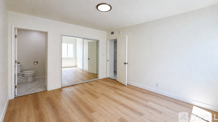 A spacious room with a wooden floor and white walls.