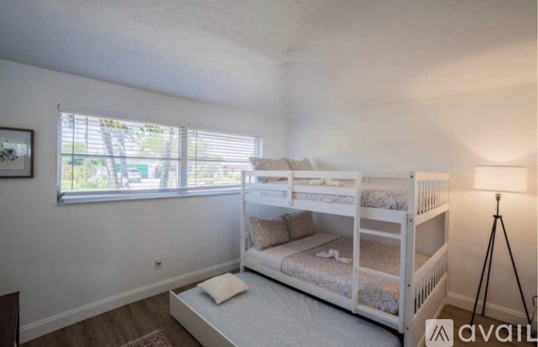 A bedroom with a bunk bed and a window with blinds.