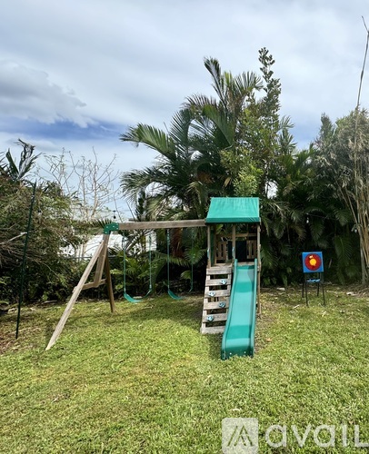 A playground with a green slide and a wooden swing set.