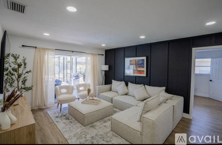 A living room with a white sofa set and a large window with curtains.