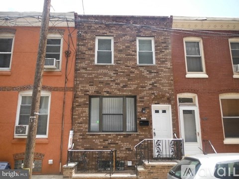 A brick building with a white door and a black railing.