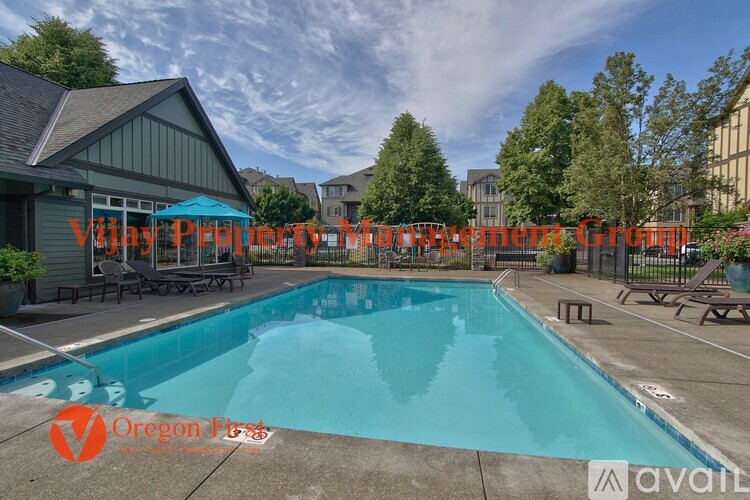 A swimming pool with a blue umbrella and lounge chairs in front of a building with the text "Village Property Management" on it.