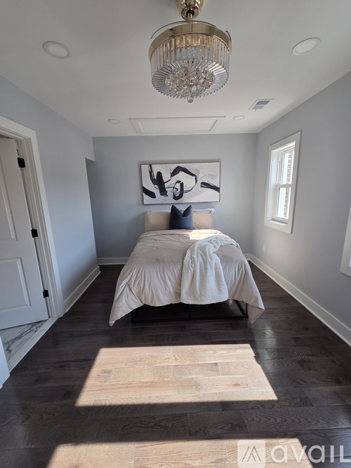 A bedroom with a bed, a chandelier, and a rug.