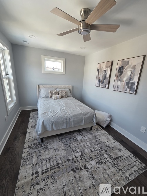 A bedroom with a bed, a ceiling fan, and two pictures on the wall.