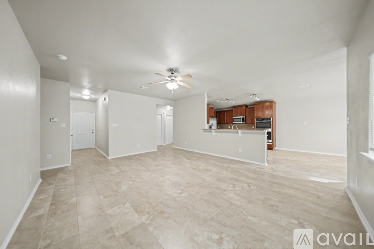 A spacious living room with a ceiling fan and lighting fixture.