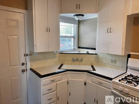 A kitchen with white cabinets and a black countertop.