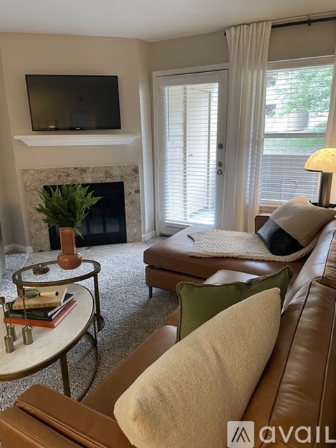 A living room with a fireplace, a couch, a chair, a coffee table, and a television mounted above the fireplace.