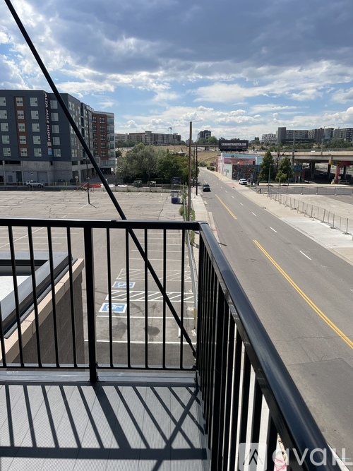 A view from a balcony overlooking a city street with cars and buildings.