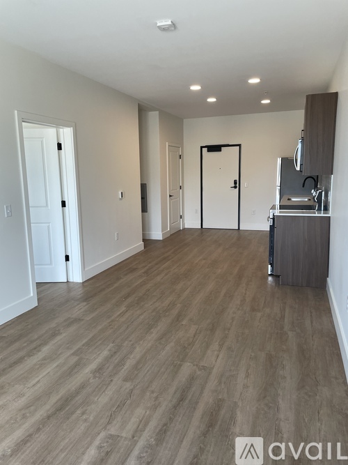 A spacious room with wooden flooring and white walls.