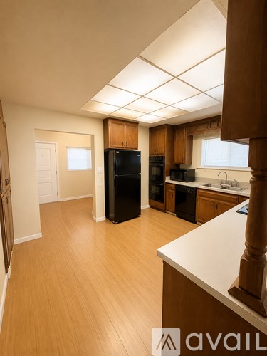 A kitchen with wooden cabinets and a black refrigerator.