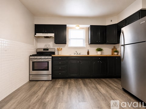 A modern kitchen with black cabinets and a stainless steel refrigerator.