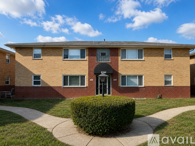 A brick apartment building with a black awning and a small front yard.