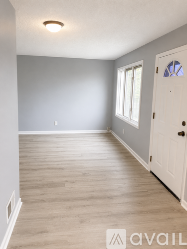 A room with a white door and a window with white blinds.