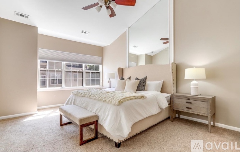 A bedroom with a large bed, a bench, and a ceiling fan.